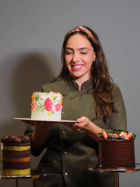 Nathália Finco segurando um bolo artesanal com pintura floral